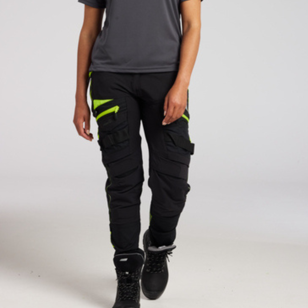 Person wearing black cargo pants with neon green accents on a white background